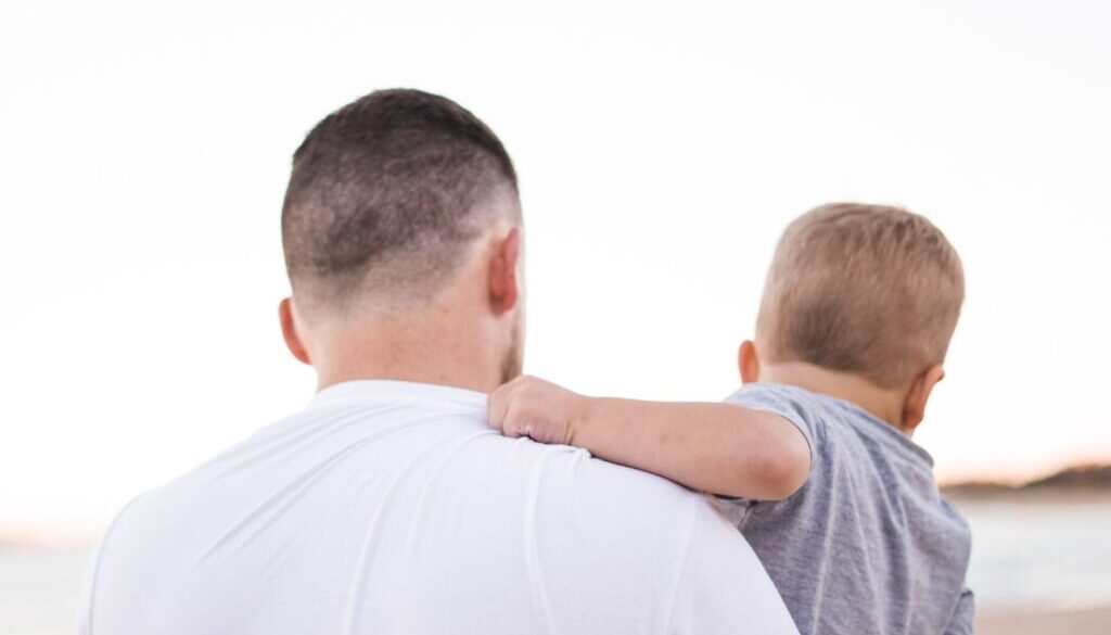 man carrying baby near the ocean
