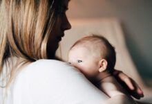 woman in white shirt carrying baby