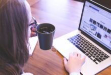 woman holding tea filled mug using MacBook