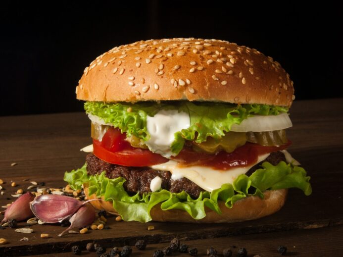 hamburger with vegetables on wooden surface