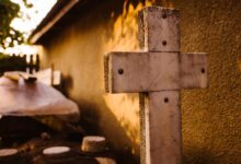 gray wooden cross on brown concrete wall