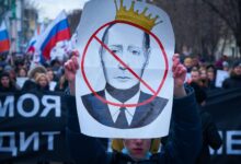 man in blue jacket holding white and red bird print banner