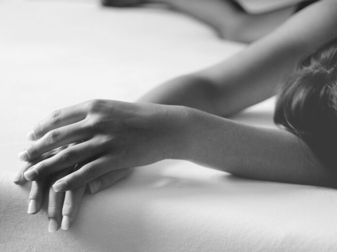 grayscale photo of person lying on bed