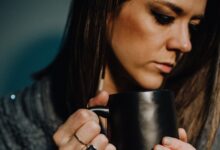 woman in black and white sweater holding black ceramic mug