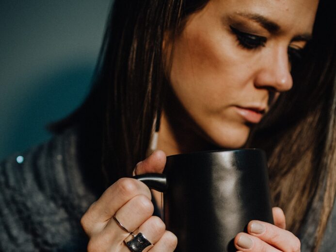 woman in black and white sweater holding black ceramic mug
