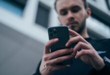 man wearing black sweater using smartphone