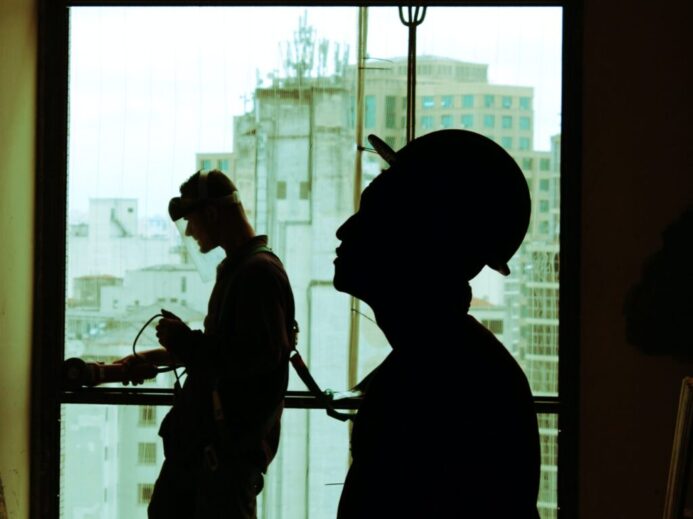 two men wearing hard hat standing near clear glass window