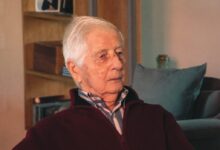 man in red and black jacket sitting on black couch