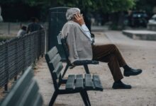 man in brown jacket sitting on bench