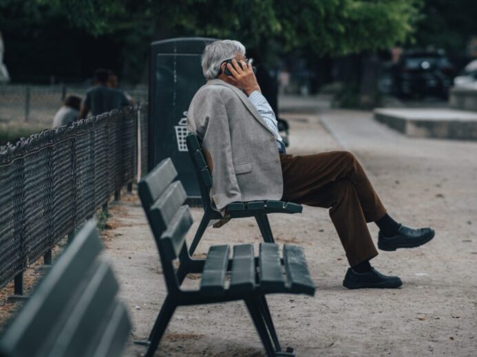 man in brown jacket sitting on bench