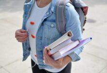 woman wearing blue denim jacket holding book