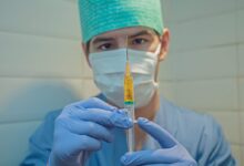 person in blue knit cap holding clear glass tube