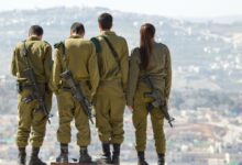 three men and one woman soldiers standing on rock during daytime