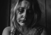 grayscale photo of woman crying holding her right chest