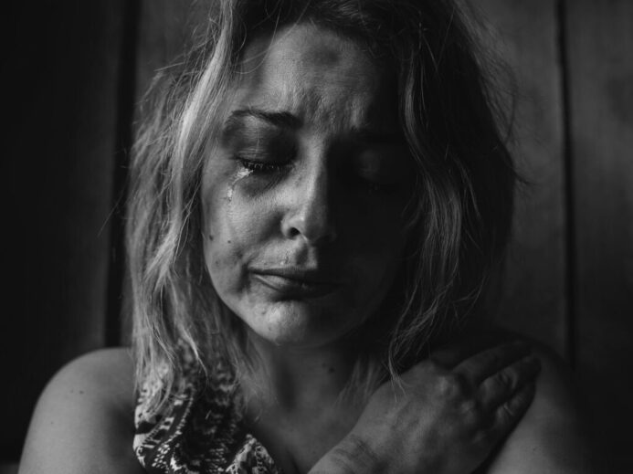 grayscale photo of woman crying holding her right chest