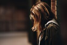 woman leaning against a wall in dim hallway