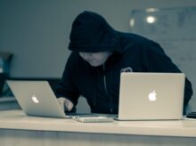 man in black hoodie using macbook
