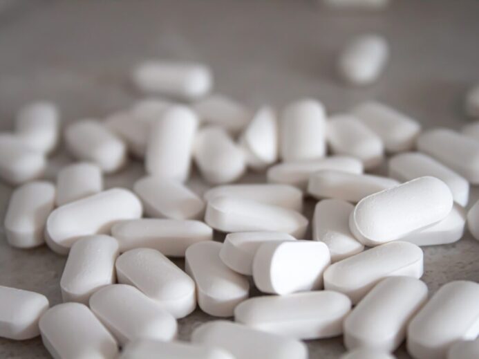 white medication pills on brown surface