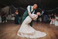 man in black suit jacket holding woman in white wedding dress
