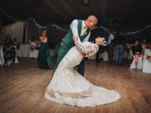 man in black suit jacket holding woman in white wedding dress
