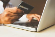 person using laptop computer holding card