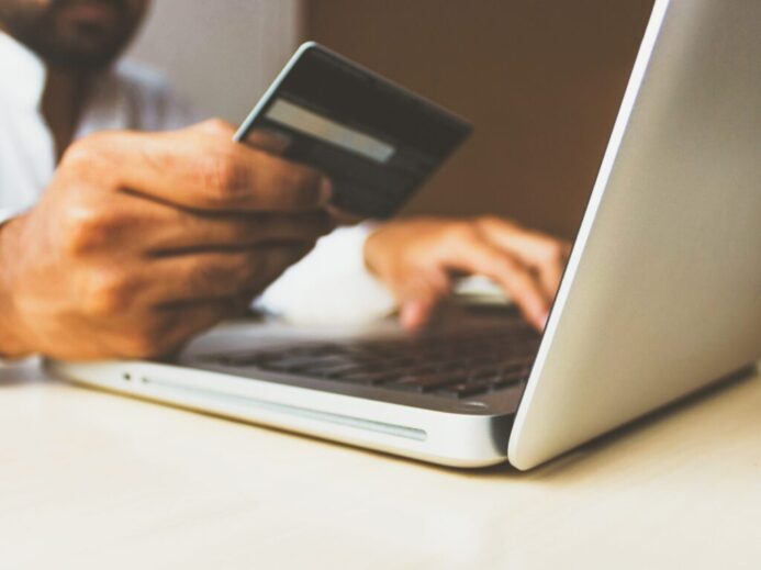 person using laptop computer holding card