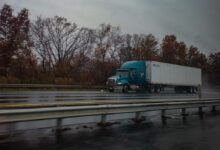 blue truck on road near bare trees during daytime