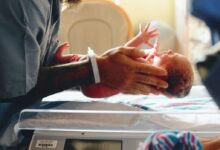 person wearing gray shirt putting baby on scale