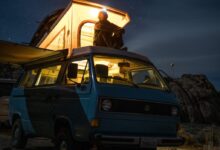 man sitting on top of blue van staring at sky during nighttime
