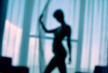sillouehtte photo of woman standing beside window curtains