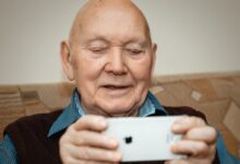 man in blue and black pinstripe dress shirt holding white smartphone