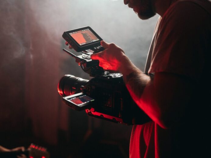 man in white t-shirt holding black video camera