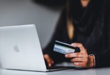 woman holding black smartphone near silver macbook