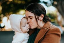 woman in brown coat hugging woman in white knit cap
