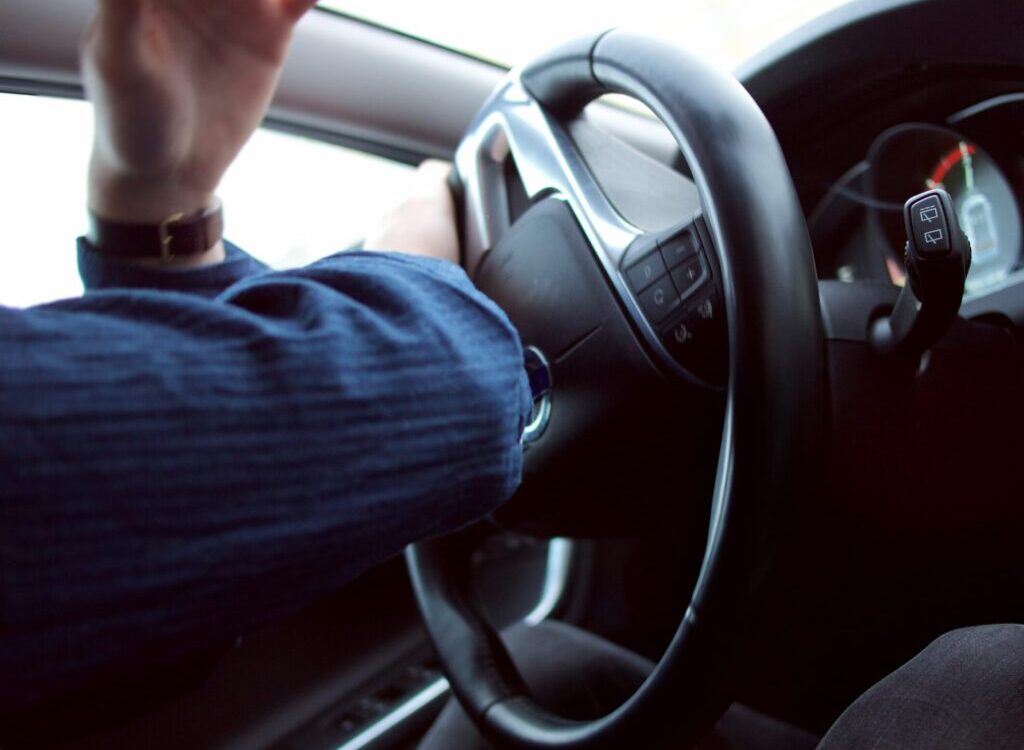 man holding black steering wheel