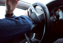 man holding black steering wheel