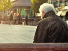 man sitting on brown wooden bench