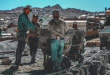 construction workers standing near wheelbarrows near mountain