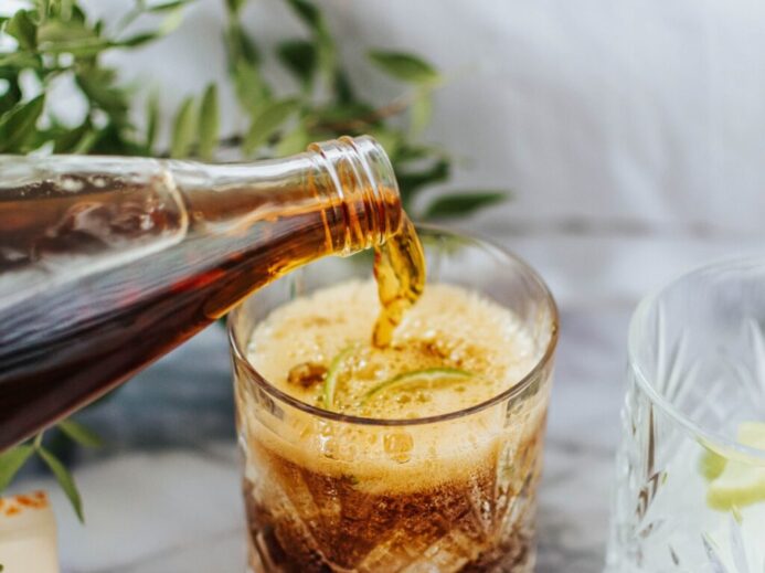 clear drinking glass with ice and brown liquid