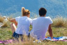 man iand woman in white shorts sitting on hill