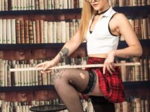 woman in white tank top and red skirt sitting on brown wooden book shelf