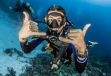 man underwater making hand signs