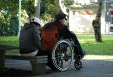 man in black jacket sitting on brown wooden bench during daytime