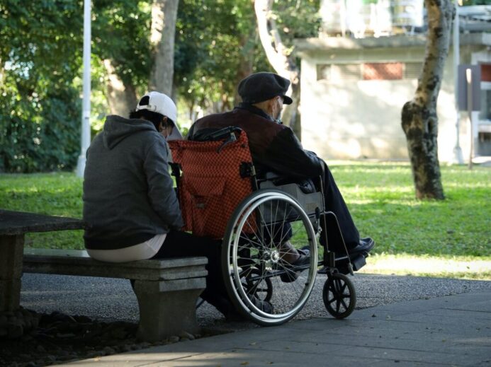 man in black jacket sitting on brown wooden bench during daytime