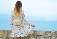 woman in white dress looking at body of water