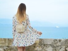 woman in white dress looking at body of water