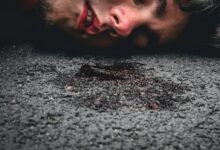 man in red sweater lying on ground during daytime