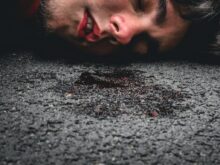man in red sweater lying on ground during daytime