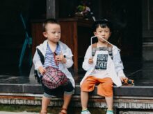 2 boys sitting on brown wooden bench