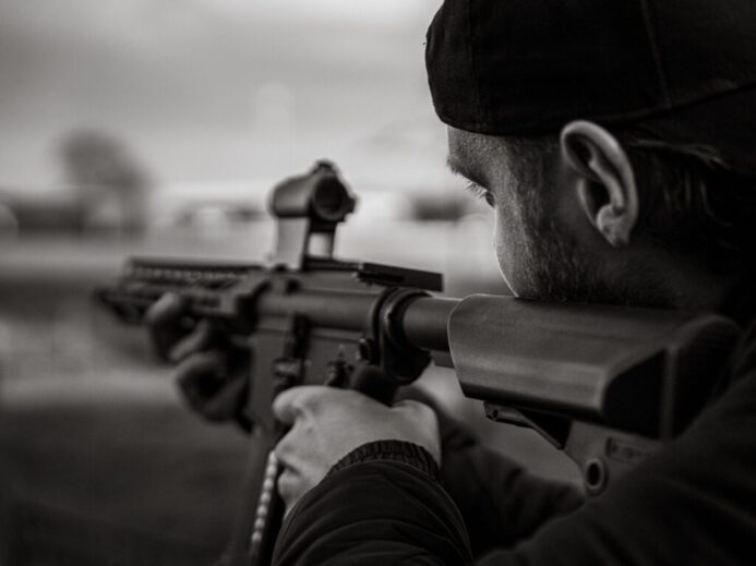 man in black knit cap holding rifle